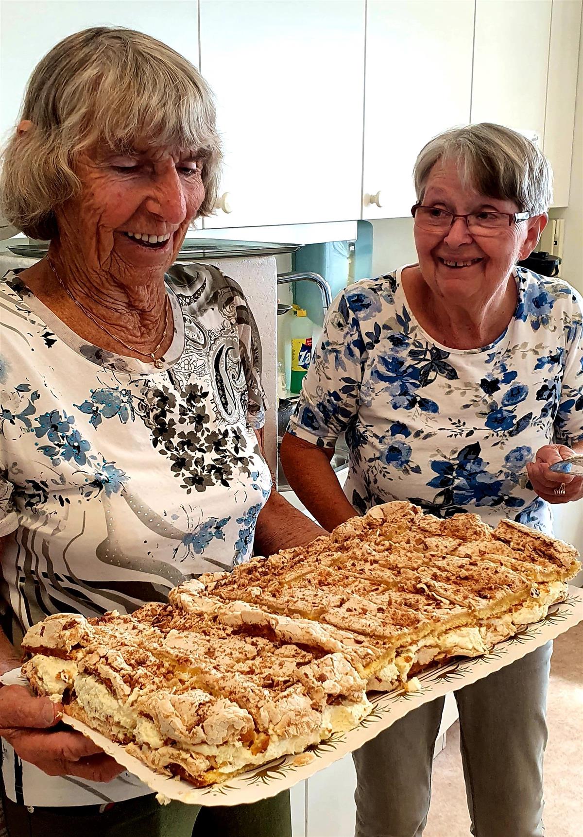 To eldre damer viser stolt fram eit nydeleg bakverk av typen "verdas beste". - Klikk for stort bilete
